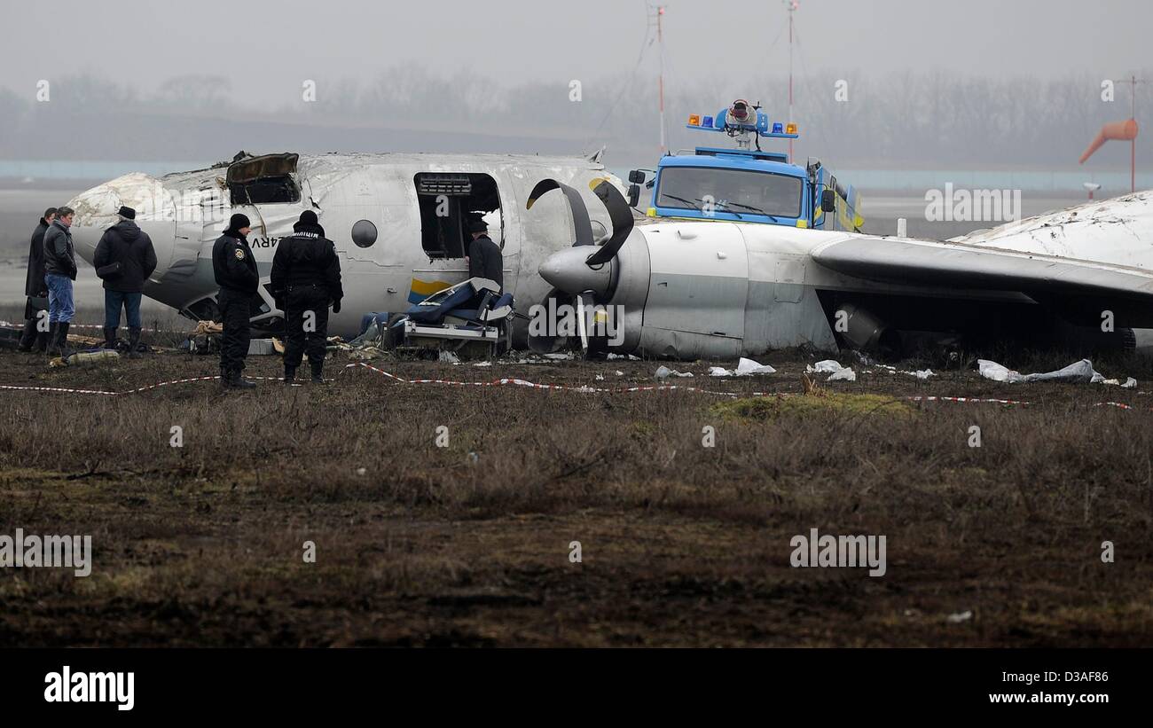 Einsatzkräfte stehen neben eines abgestürzten Flugzeugs auf dem Flughafen in Donezk, Ukraine, 14. Februar 2013. Mindestens fünf Menschen wurden nach einer An-24 Flugzeug Bruchlandung in der Nähe des Flughafens von der Ost-ukrainischen Stadt Donezk, tot wie Beamte sagten. Foto: Marius Becker/dpa Stockfoto