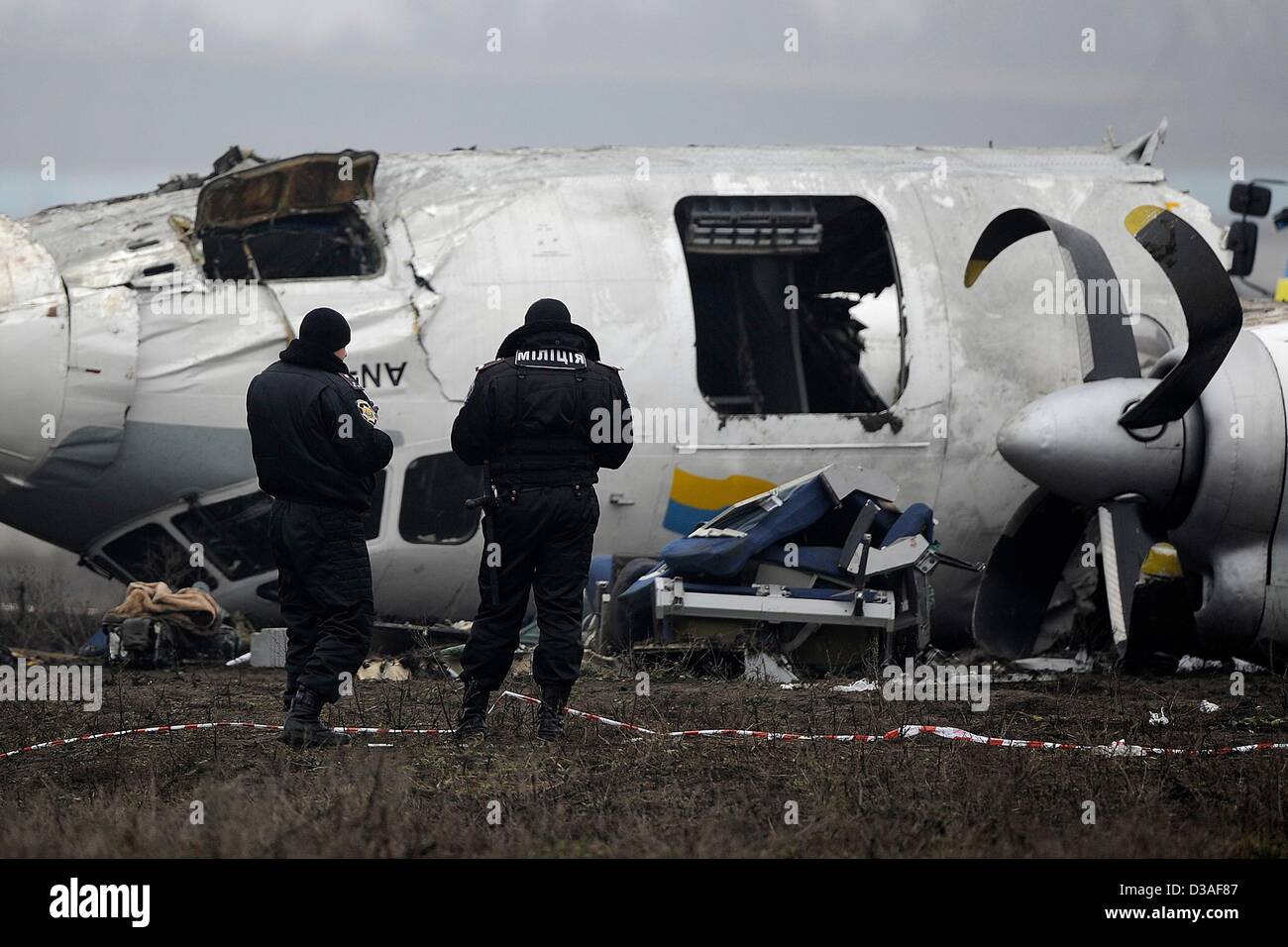 Einsatzkräfte stehen neben eines abgestürzten Flugzeugs auf dem Flughafen in Donezk, Ukraine, 14. Februar 2013. Mindestens fünf Menschen wurden nach einer An-24 Flugzeug Bruchlandung in der Nähe des Flughafens von der Ost-ukrainischen Stadt Donezk, tot wie Beamte sagten. Foto: Marius Becker/dpa Stockfoto