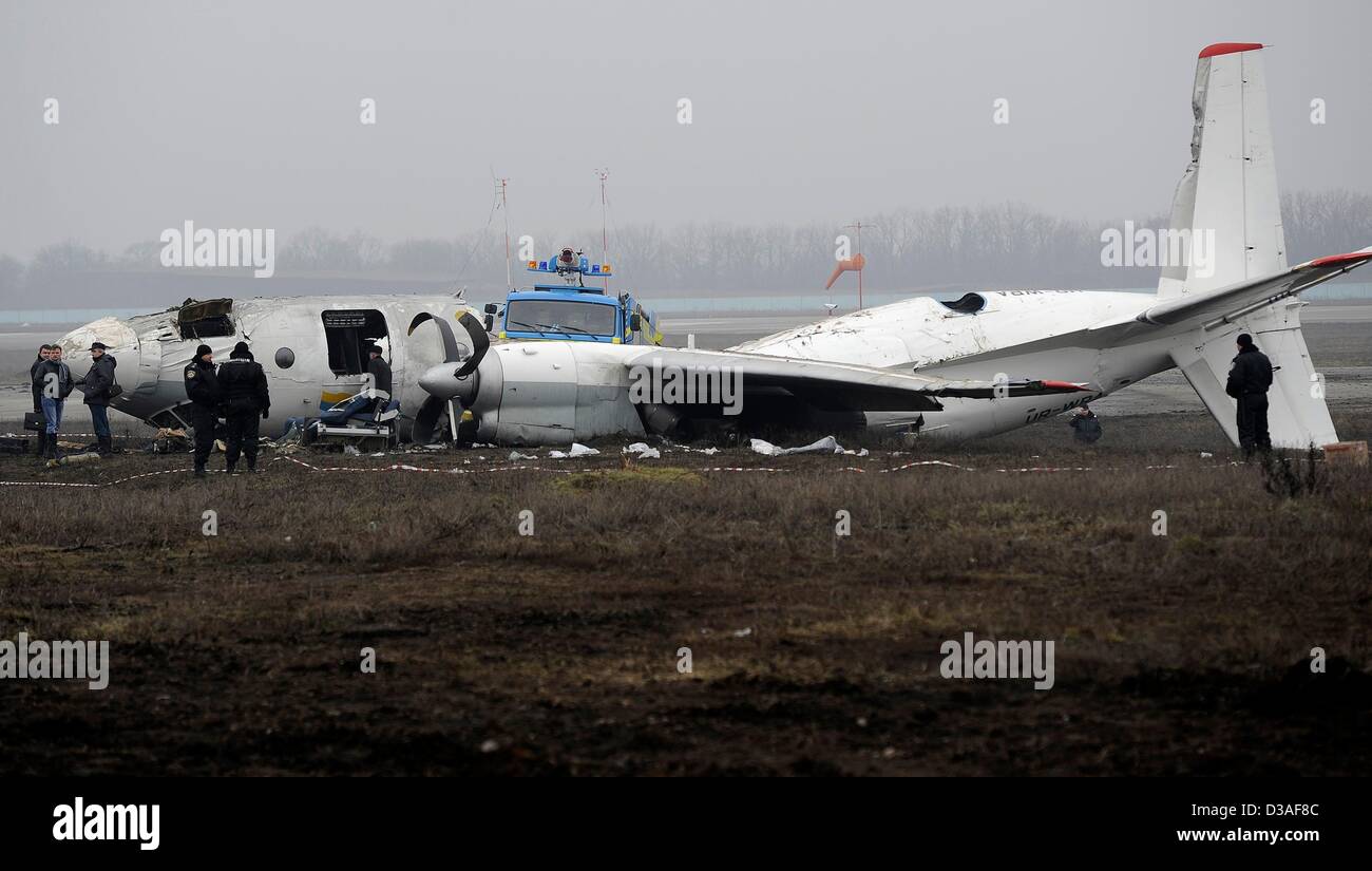 Einsatzkräfte stehen neben eines abgestürzten Flugzeugs auf dem Flughafen in Donezk, Ukraine, 14. Februar 2013. Mindestens fünf Menschen wurden nach einer An-24 Flugzeug Bruchlandung in der Nähe des Flughafens von der Ost-ukrainischen Stadt Donezk, tot wie Beamte sagten. Foto: Marius Becker/dpa Stockfoto