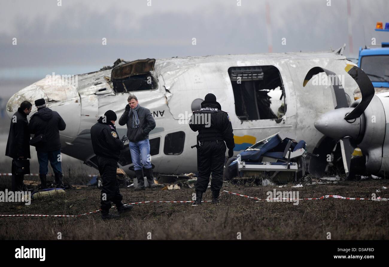 Einsatzkräfte stehen neben eines abgestürzten Flugzeugs auf dem Flughafen in Donezk, Ukraine, 14. Februar 2013. Mindestens fünf Menschen wurden nach einer An-24 Flugzeug Bruchlandung in der Nähe des Flughafens von der Ost-ukrainischen Stadt Donezk, tot wie Beamte sagten. Foto: Marius Becker/dpa Stockfoto