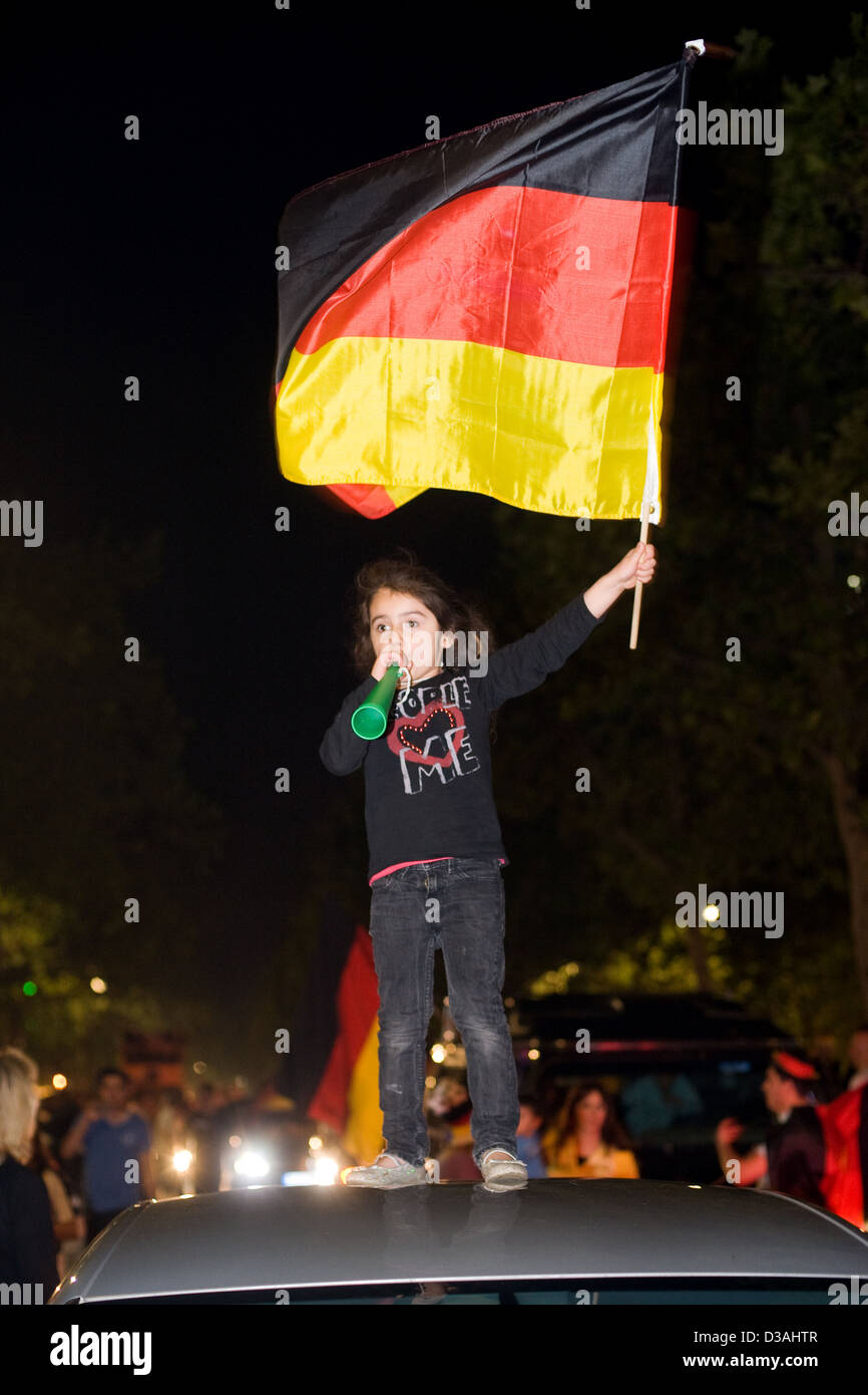 Berlin, Deutschland, schwang eine Mädchen auf einem Autodach die Deutschland-Flagge Stockfoto