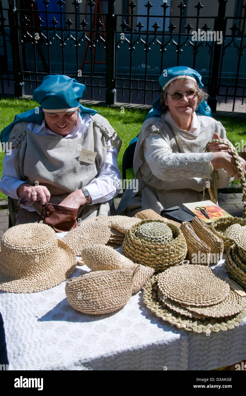 Zwei lettische Frauen in mittelalterlicher Tracht, Strohhüte für den Verkauf auf der jährlichen lettischen Kulturfestival in der Altstadt von Riga, Riga, La Stockfoto