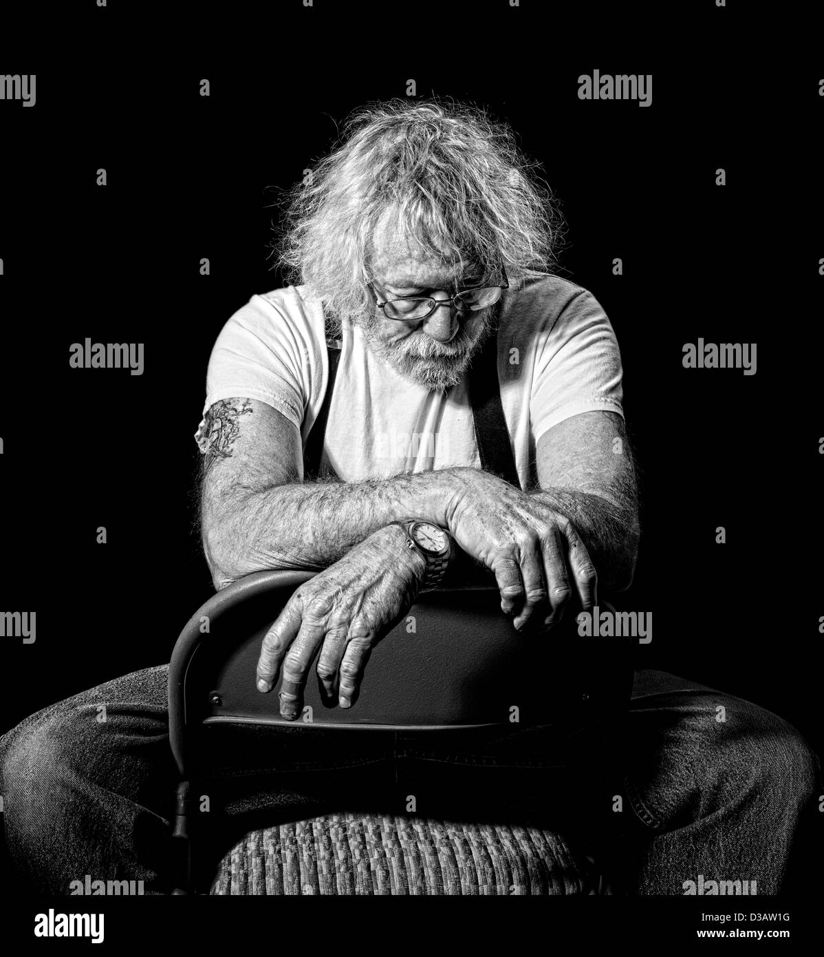 Senior mit verschränkten auf einem Stuhl mit einem Blick der Niedergeschlagenheit in Monochrom isoliert auf schwarz Stockfoto