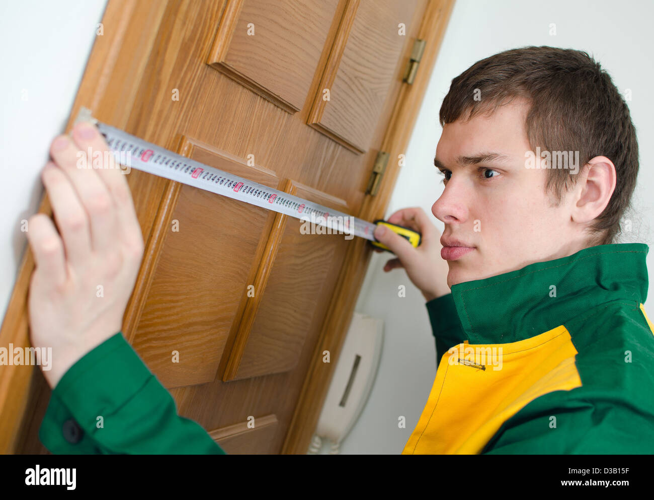 Junge Handwerker in Uniform mit Maßband Stockfoto