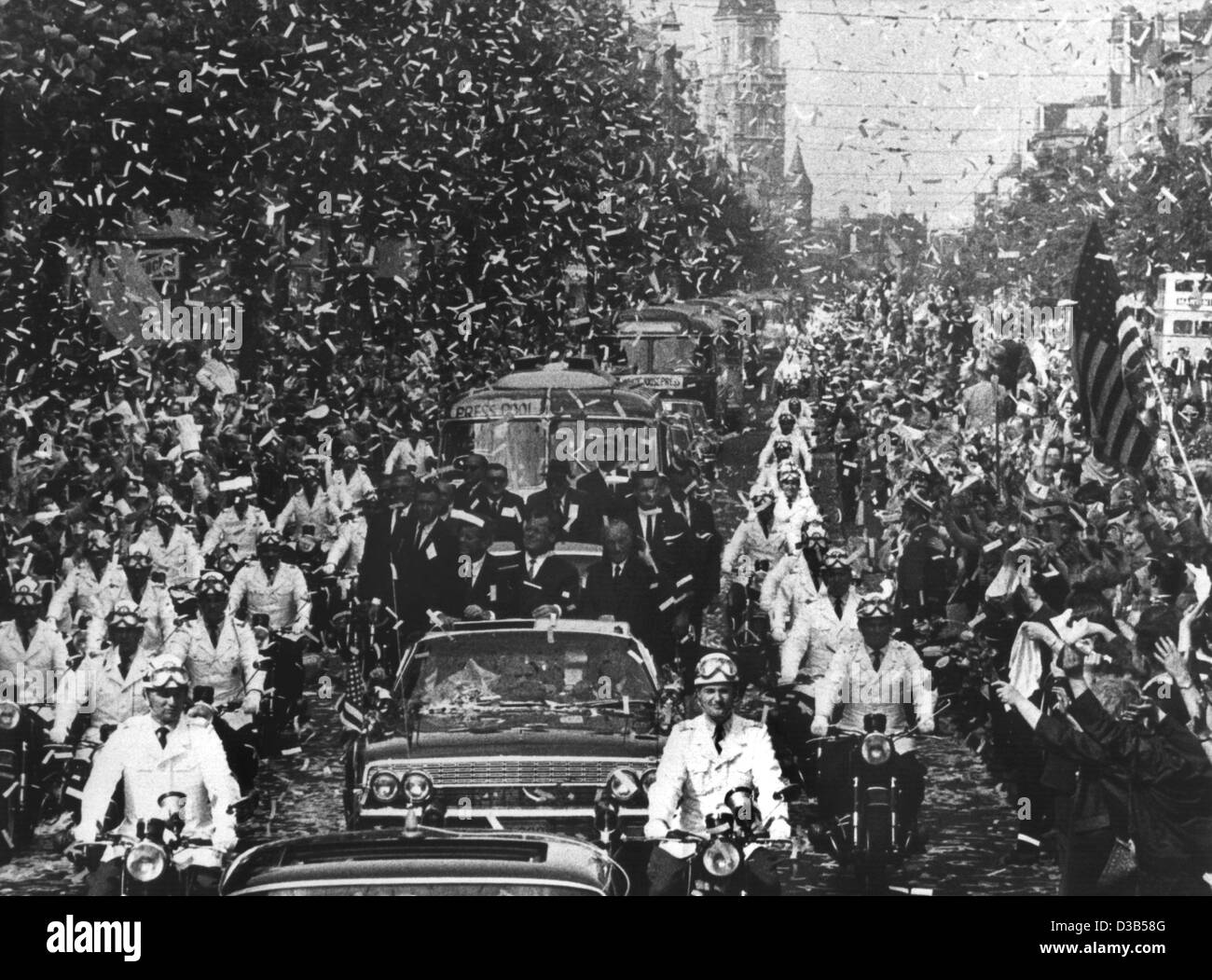 (Dpa-Dateien) - US Präsident John F. Kennedy (L) wird mit einem Konfetti-Regen gefeiert, als er in einer offenen Limousine durch die Rheinstraße in West-Berlin, 26. Juni 1963 begleitet wird. Der Präsident wird im Auto von Berlin Mayor Willy Brandt (C) und German Chancellor Konrad Adenauer (R) begleitet. Die clim Stockfoto