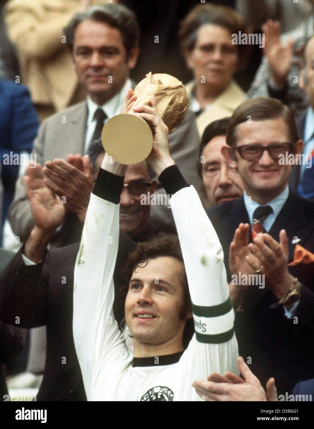 (Dpa-Dateien) - Franz Beckenbauer, dann deutsche Mannschaftskapitän hebt glücklich "Coupe Jules Rimet" nach dem Gewinn der Fußball-Weltmeisterschaft in München, 7. Juli 1974. Direkt hinter Beckenbauer applaudiert Pieter van Vollenhofen. Deutschland besiegt die Niederlande im Finale mit 2:1. Stockfoto