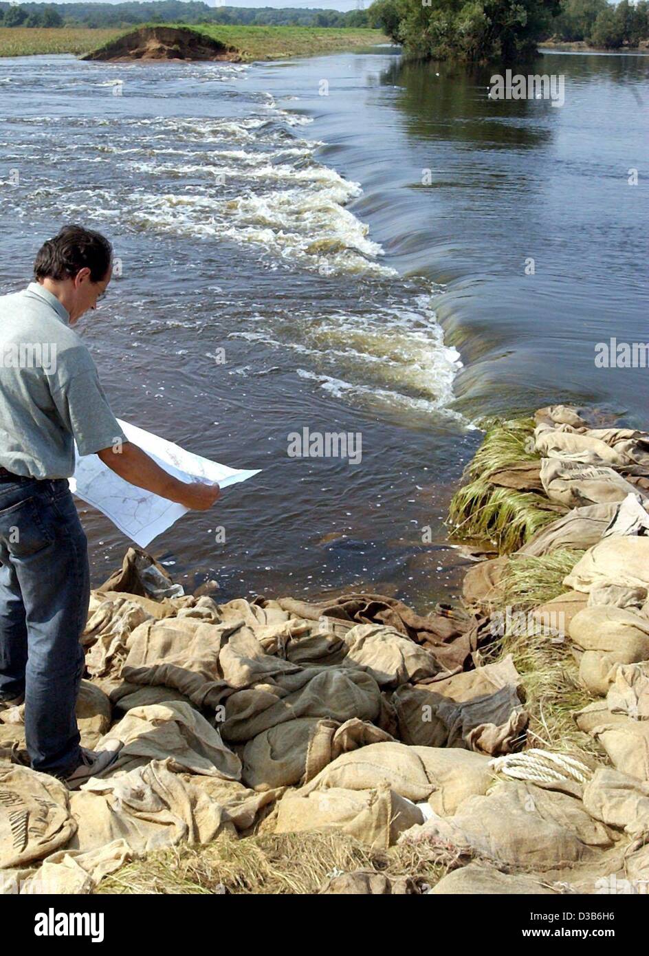 (Dpa) - ein Mitarbeiter der Kreisverwaltung prüft eine Verletzung in einem Damm in der Nähe von Seegrehna, Ostdeutschland, 25. August 2002. Die Sprengung eines Teils des Dammes wird noch kontrovers diskutiert: der Wasserspiegel sank 30 cm, aber das Wasser des Flusses Elbe weiterhin durch den Spalt fließen und Stockfoto