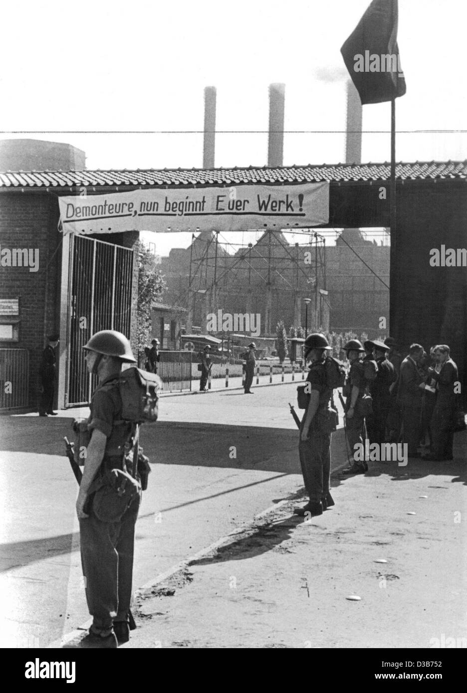 (Dpa-Dateien) - britische Soldaten bewachen die Straße zum Eingang des Chemiewerks Ruhrchemie in Oberhausen, Deutschland, 5. September 1949. Die Fahne auf dem Tor lautet: "Altautoverwerter, jetzt beginnen Ihre Arbeit!" Stockfoto
