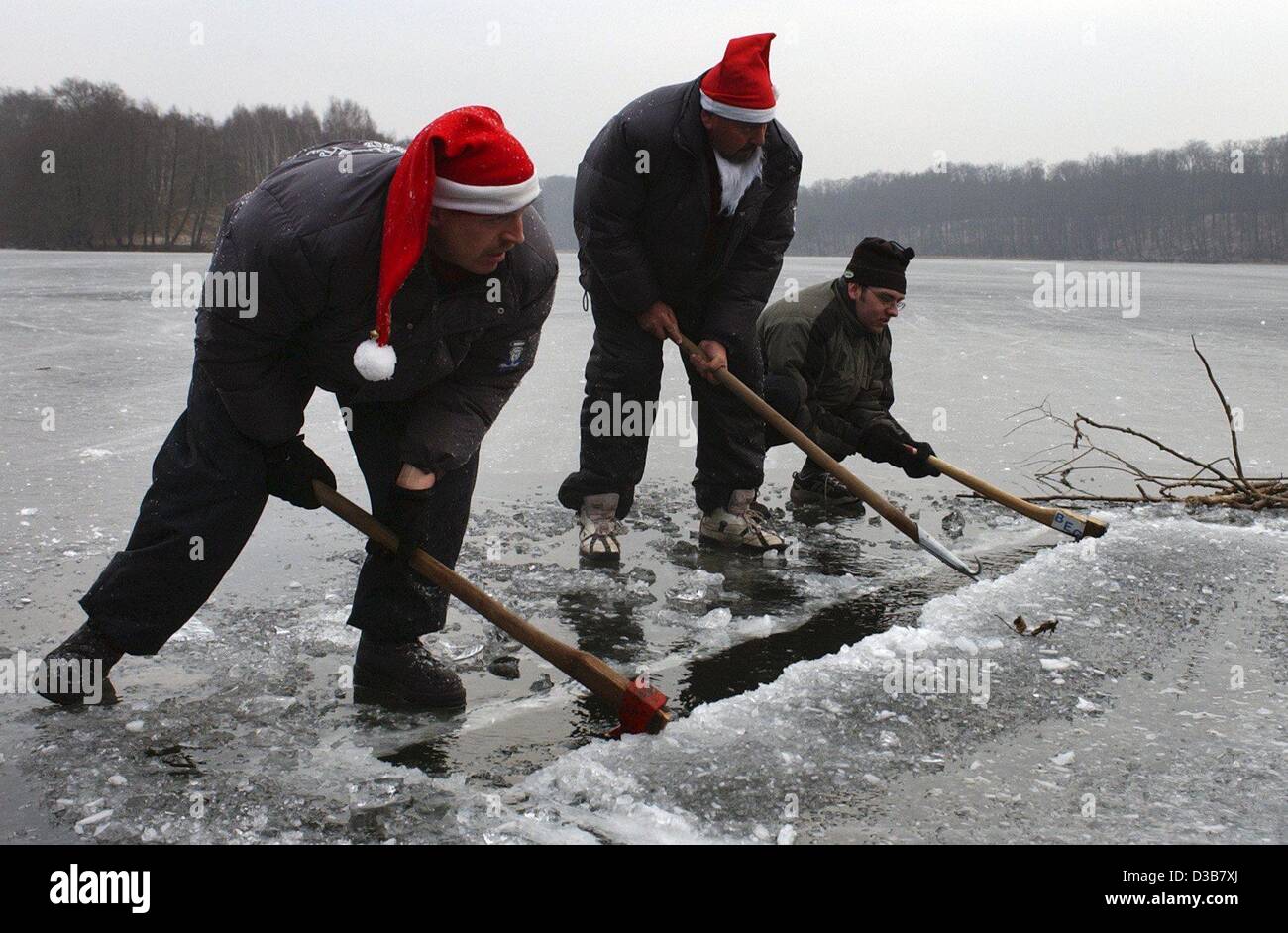 Dpa) - Menschen mit Sankt Nikolaus Hüte auf den Köpfen graben ein großes  Loch in die Eisschicht mit Achsen, einen Pool im See Liepnitz in der Nähe  von Berlin, 15. Dezember 2002