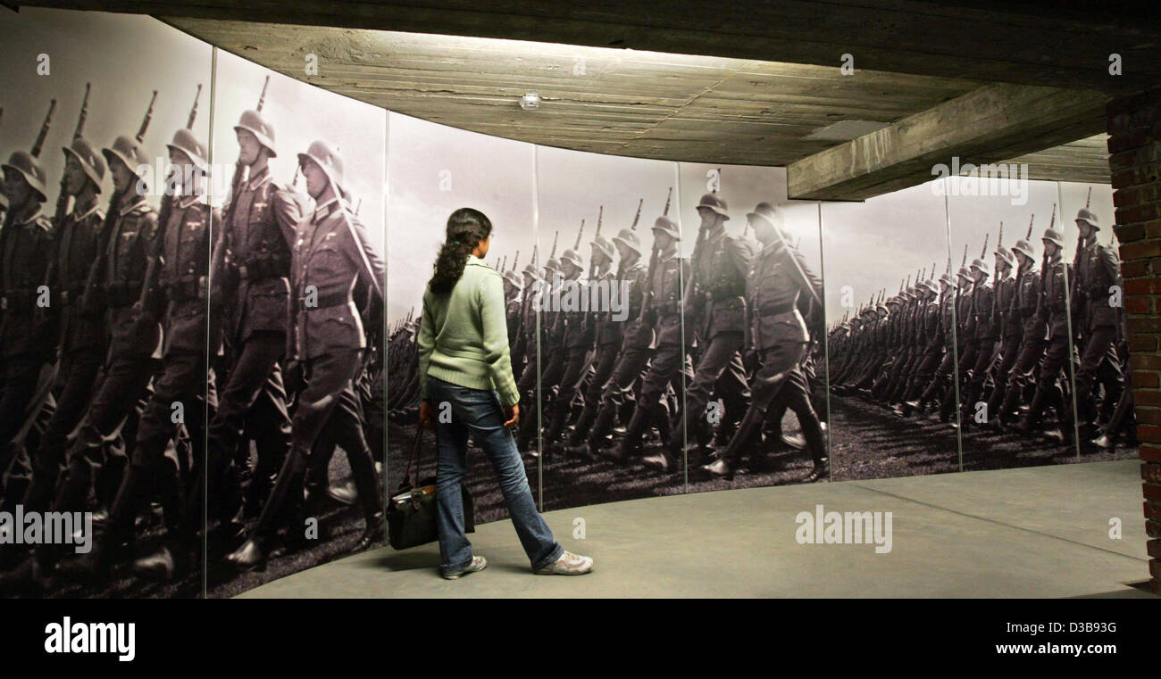 (Dpa) - steht eine junge Frau vor einem Foto, das dass Soldaten der deutschen Wehrmacht im Zentrum der Dokumentation Reichsparteitag Bereich in Nürnberg, 7. Juli 2005 zeigt. Seit der Eröffnung im November 2001 besuchten mehr als eine halbe million Menschen das Zentrum. Die Richtung der documenta Stockfoto