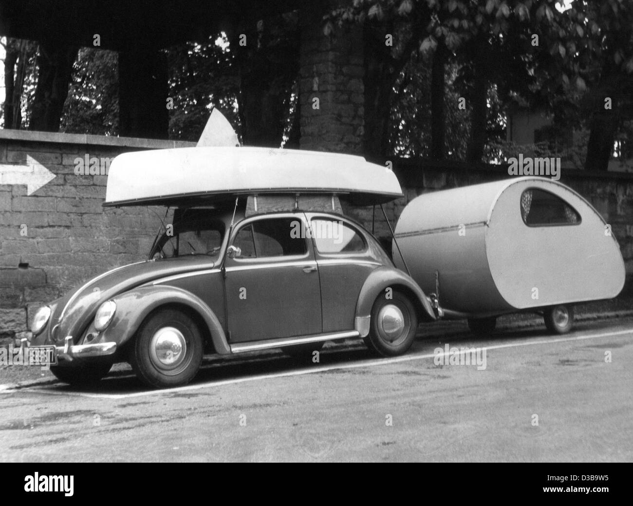(Dpa-Dateien) - ein VW Käfer mit einem Segelboot geladen und ein angebauter Wohnwagen ist bereit für die Urlaubsreise, Westdeutschland, 1956. Stockfoto