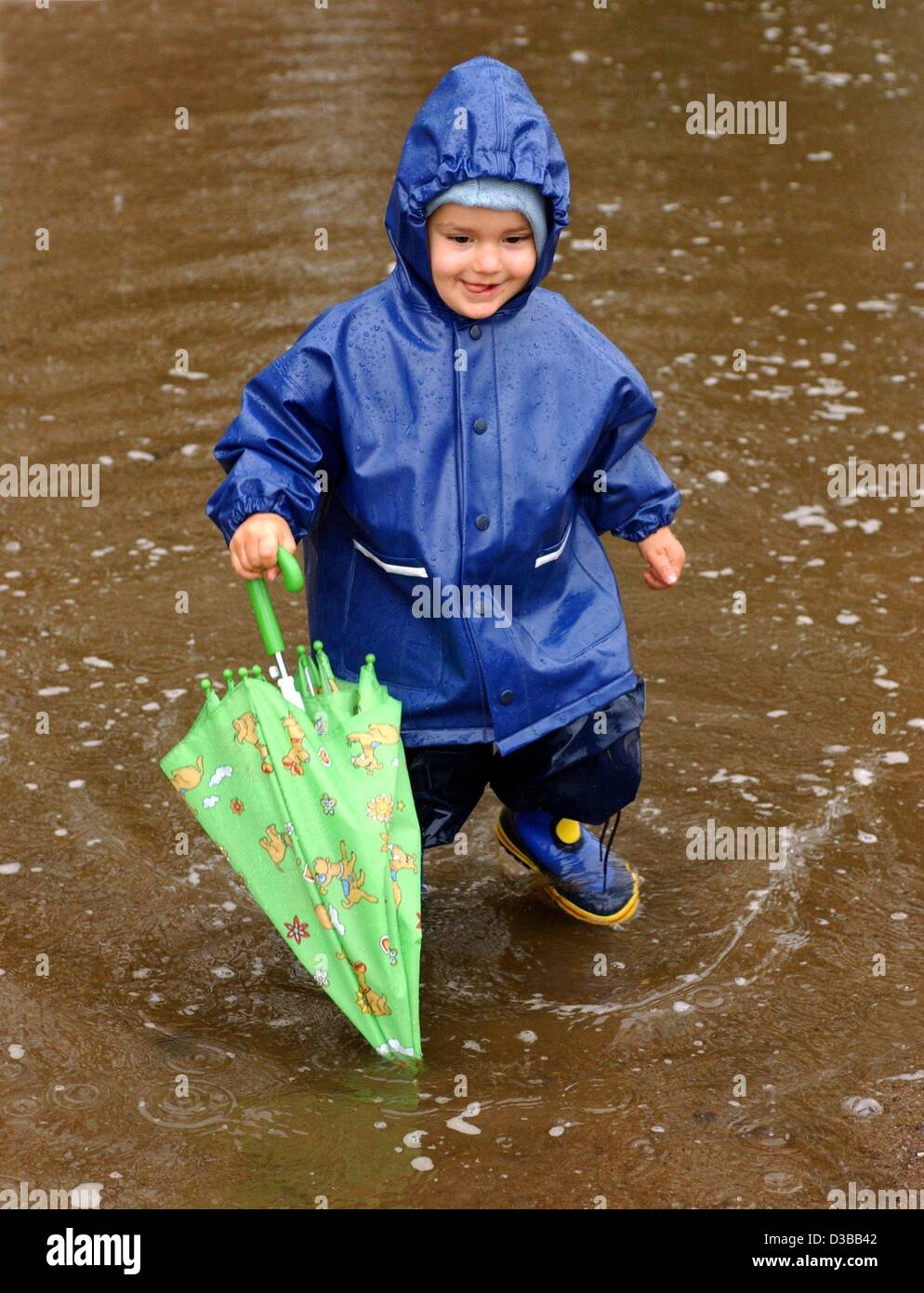 (Dpa) - "bin ich im Regen... spielen" Kleinen Damien scheint das Böse Wetter zu genießen, da er durch eine Pfütze in einem kompletten Regen-Outfit in Frankfurt Oder, Ostdeutschland, 6. Oktober 2002 läuft. Stockfoto