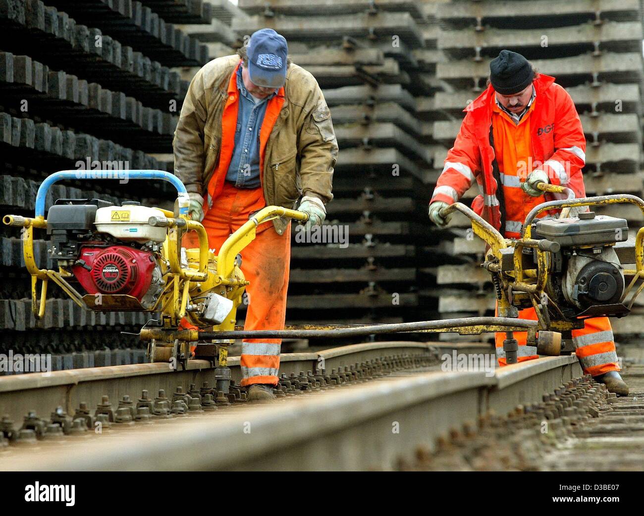 (Dpa) - Arbeitnehmer von der Deutsche Bahn AG Deutsche Bahn demontieren gesamte Gleise in Duisburg, Deutschland, 20. Januar 2003. Die Schrauben der Schwellen sind mit motor angetriebenen Maschinen, die als Schraubendreher gelöst. Stockfoto