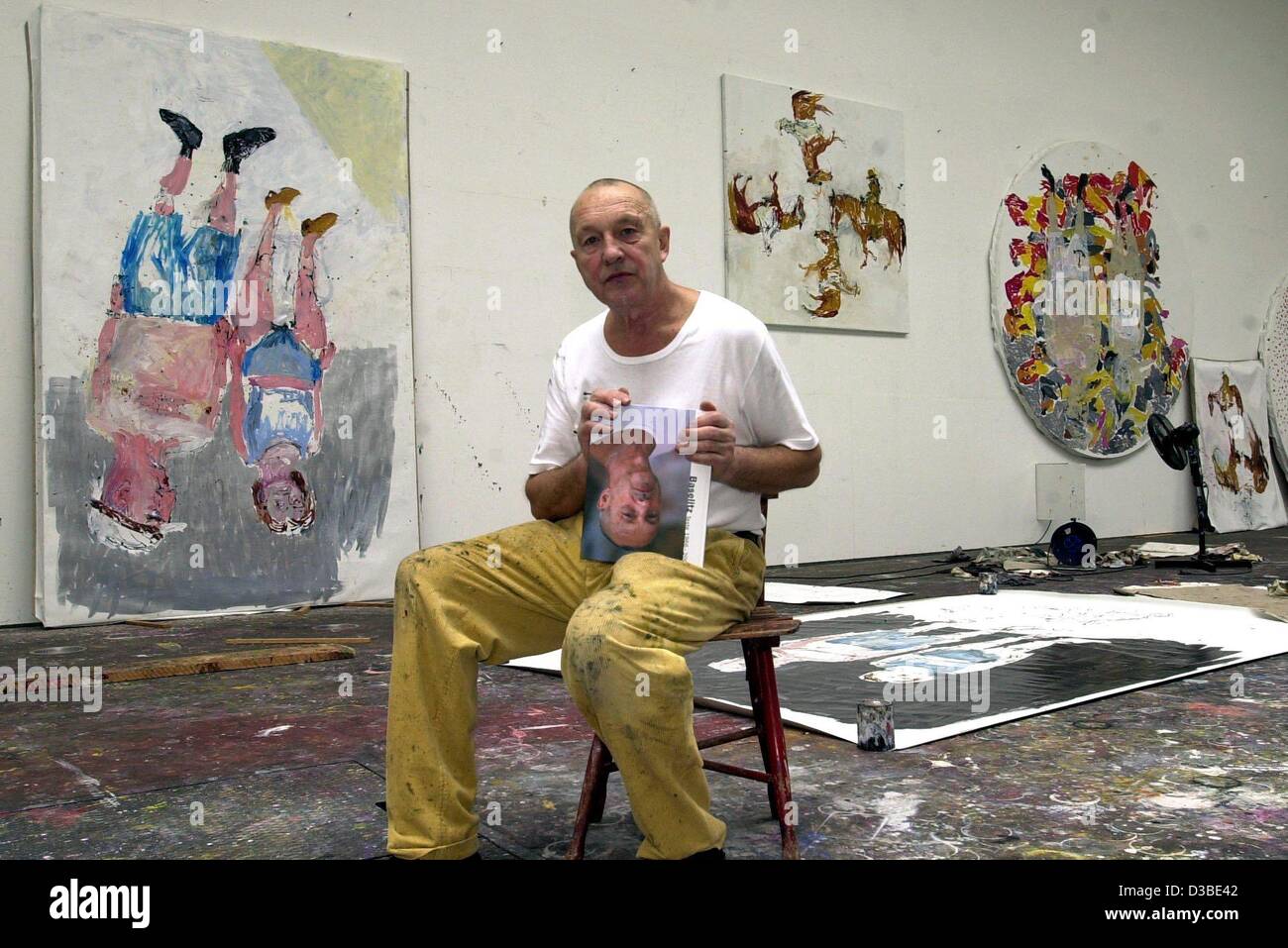 (Dpa) - Künstler Georg Baselitz ist in seinem Atelier hält ein Buch mit dem Kopf auf dem Cover kopfüber, Derneburg, Deutschland, 21. Januar 2003 sitzen. Er deutet auf seinen berühmten Kopfstand-Bildern, die ersten als "Wald Auf Dem Kopf" (Wald gedreht) vor 30 Jahren. Baselitz zählt zu den am meisten ich Stockfoto