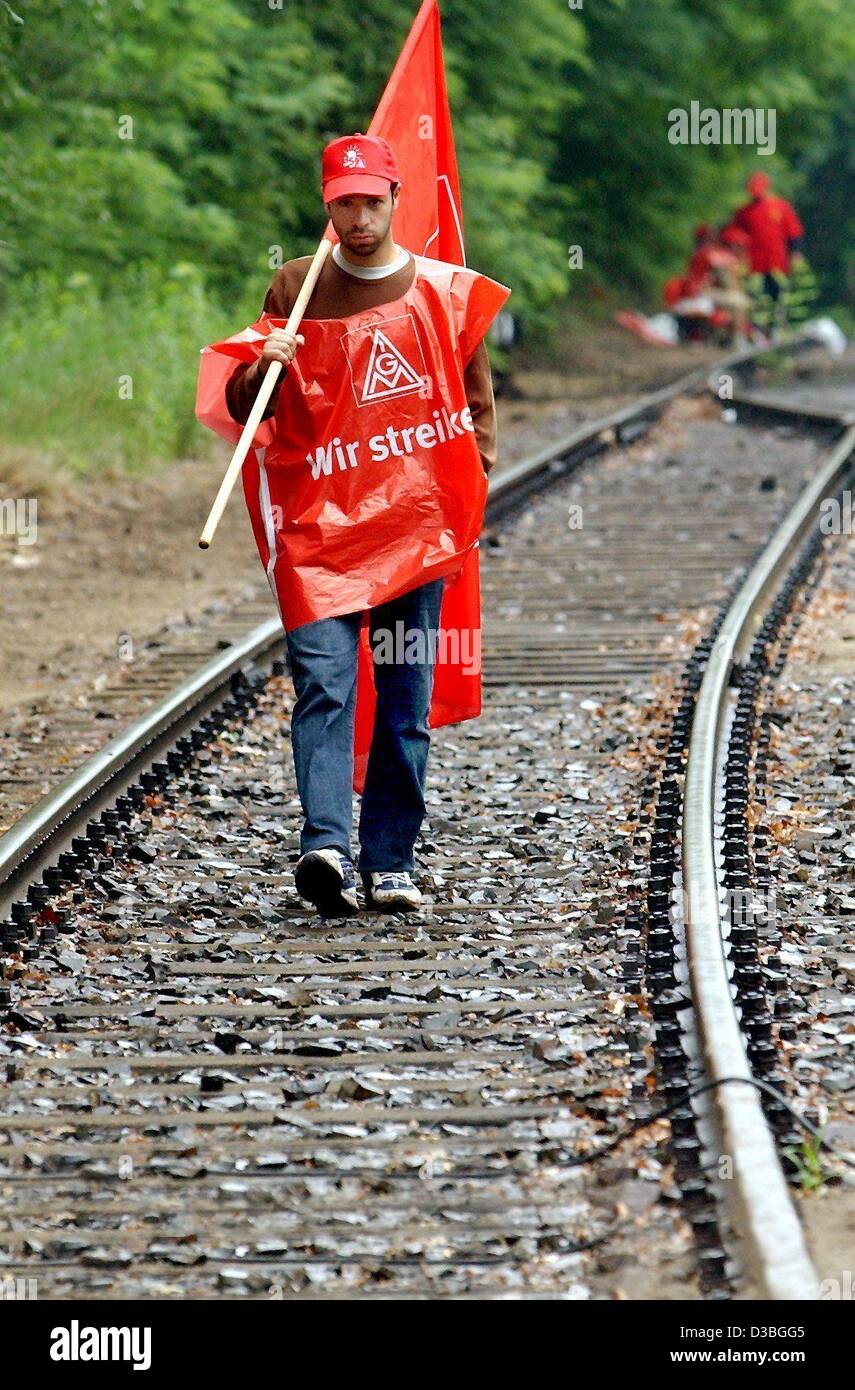 (Dpa) - ein Streik Streikposten ist ausgestattet mit Flagge und Hemd von der deutschen Metall Gewerkschaft IG Metall, wie er zwischen den Tracks in der Nähe von einem Industriegelände in Dresden, 18. Juni 2003 geht. Die Arbeiter wollten Industrie Autozulieferer Federal Mogul von Lieferungen abgeschnitten, aber die Firma hat Material und Mensch Stockfoto