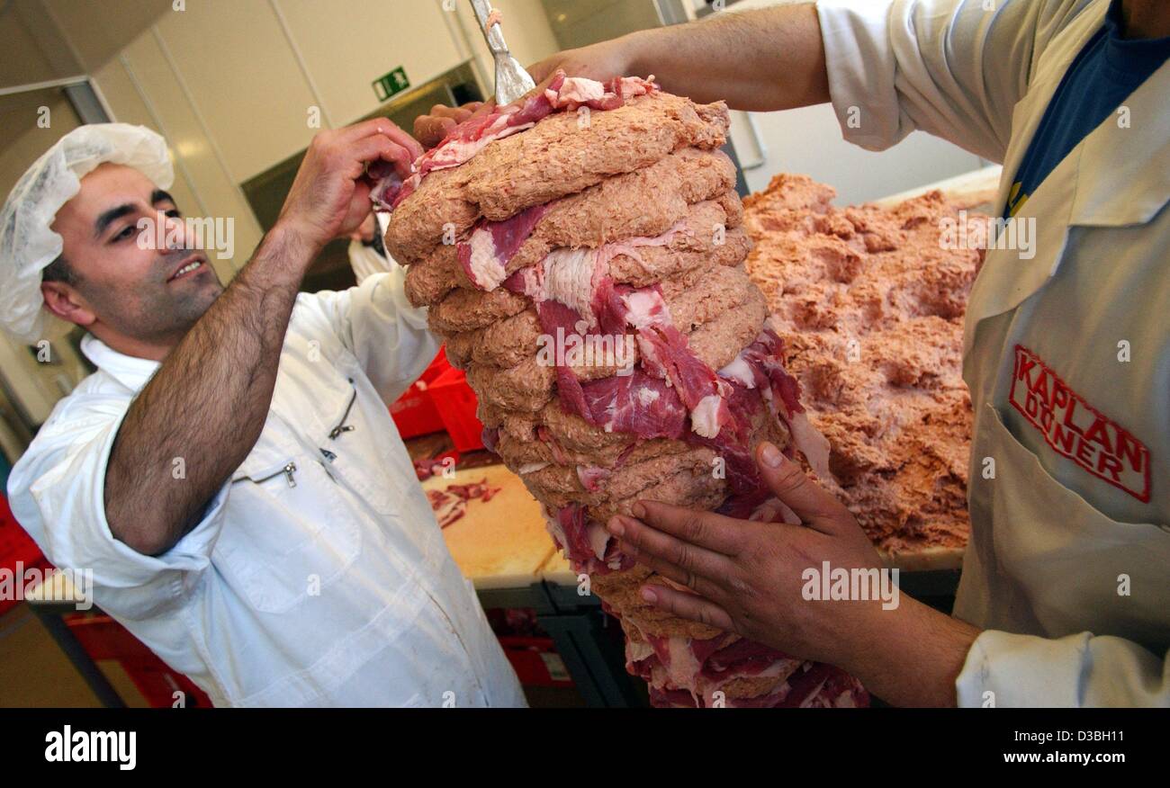 (Dpa) - ein Mitarbeiter von Kaplan Doenerproduktion, Produzent von Dönerfleisch für den Lebensmitteleinzelhandel, bereitet einen Spieß mit Kebab-Fleisch in Berlin, 15. April 2003. Fleisch vom Rind oder Geflügel, frischem Salat und Declicious waren Soße eingebettet in ein warmes Fladenbrot, das typische Döner macht. 2 Millionen ke Stockfoto