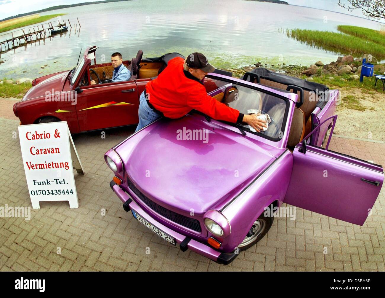 (Dpa) - Bern Quandt, Besitzer von einer Autovermietung, poliert die Windschutzscheibe lila farbigen Trabi Cabrio in Bannemin auf der Insel Usedom, Deutschland, 16. Mai 2003. Quandt läuft die Verleih-Service unter dem Namen "Fun Car Rent" als einen zweiten Job seit 1999. Die Hauptsaison dauert von Juni bis September Stockfoto