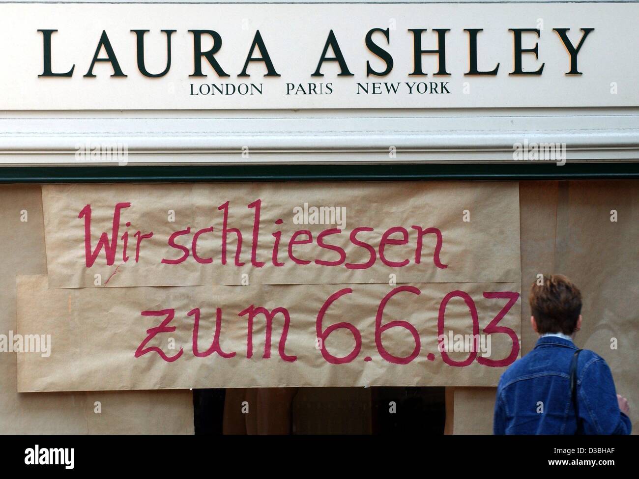 Eine Frau schaut ein Schild hängen im Schaukasten der Laura Ashley-Shop in Düsseldorf, 16. Mai 2003. Die Zeichen kündigt an, dass das Geschäft der britischen Mode-Firma von 6. Juni 2003 geschlossen werden. Stockfoto