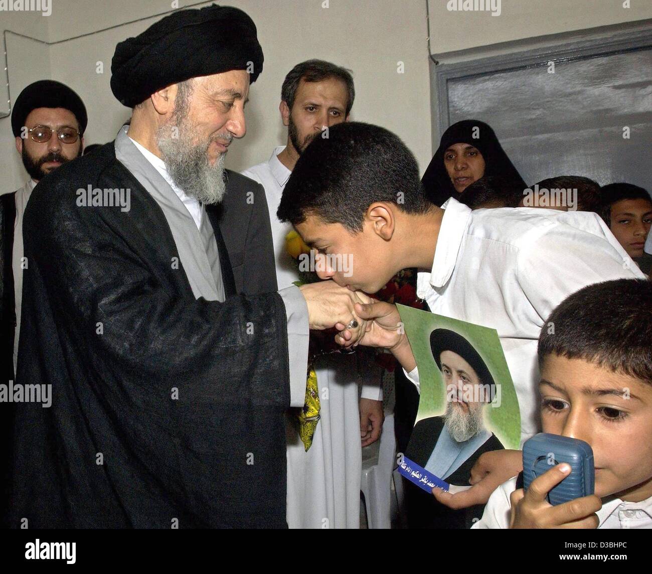 (Dpa) - eine irakische Jugend küsst die Hand des schiitischen Geistlichen Mohammed Baqir al-Hakim bei seiner Ankunft in den Obersten Rat für islamische Revolution des Irak in Nadschaf, 13. Mai 2003. Hakim, der dieses Wochenende nach 23 Jahren des Exils im Iran in den Irak zurückgekehrt ist, sagte am 12. Mai, dass Irak seinen eigenen Zug wählen müssen Stockfoto