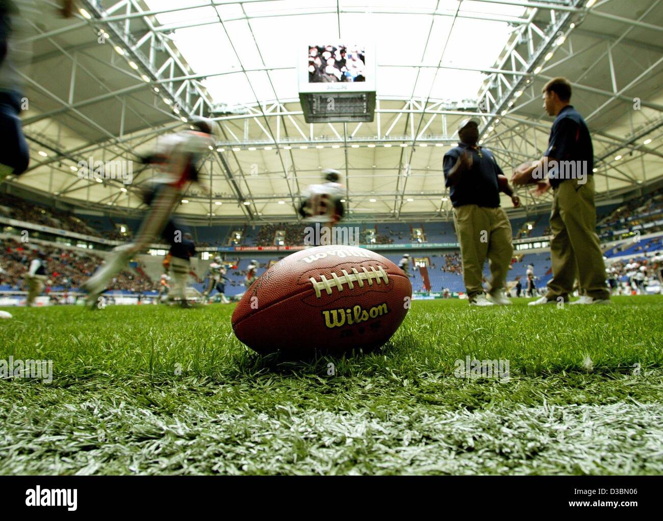 (Dpa) - Fußball liegt auf dem Spielfeld bereit und warten gespielt werden und im Hintergrund sind die Spieler der Rhein Fire Aufwärmen für das Spiel Rhein Fire gegen Amsterdam Admirals zu Beginn des American Football-Saison der NFL Europe in der AufSchalke Arena in Gelsenkirchen, Deutschland, 5 Ap Stockfoto