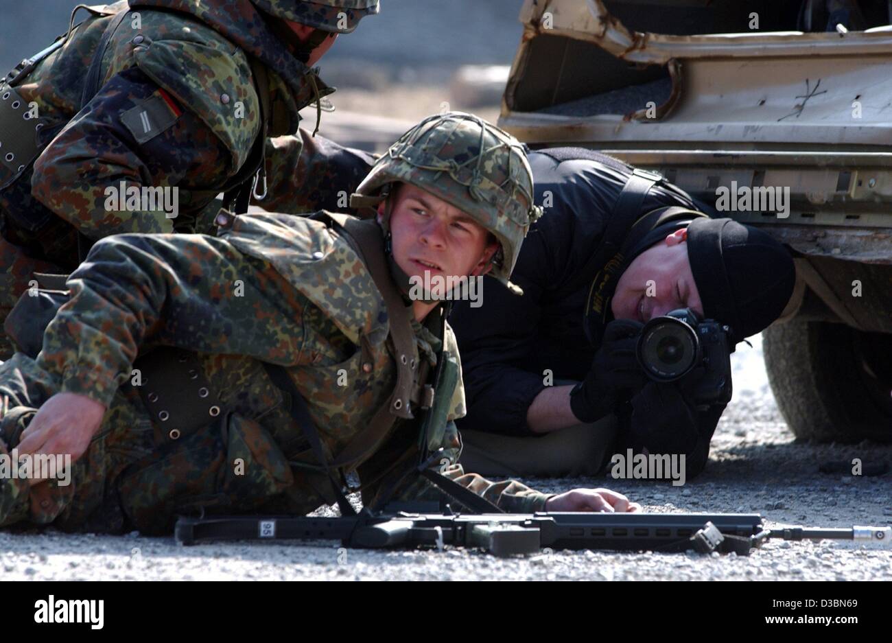 (Dpa) - ein Fotograf Kneenls vor einem Soldaten nach unten und nimmt ein Bild während eines Manövers des deutschen Heeres in Hammelburg, Deutschland, 21. März 2003. Beiden Fotografen sind Teilnehmer an einem Programm organisiert von der deutschen Armee und der deutschen Printmedien Association, die Beru Stockfoto