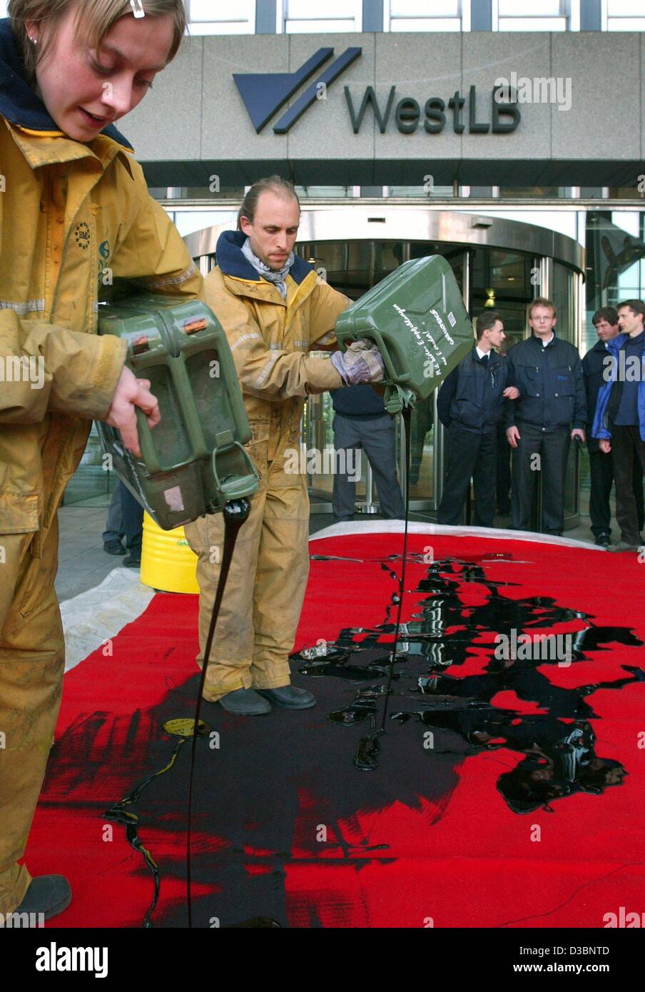 (Dpa) - Greenpeace-Aktivisten verschütten Benzin auf einem roten Teppich vor dem Hauptsitz der Westdeutschen Landesbank (WestLB) in Düsseldorf, 16. Mai 2003. Greenpeace protestiert gegen die West LB Finanzierung einer Ölpipeline in Ecuador. West LB ist Deutschlands fünftgrößte Bank. Stockfoto