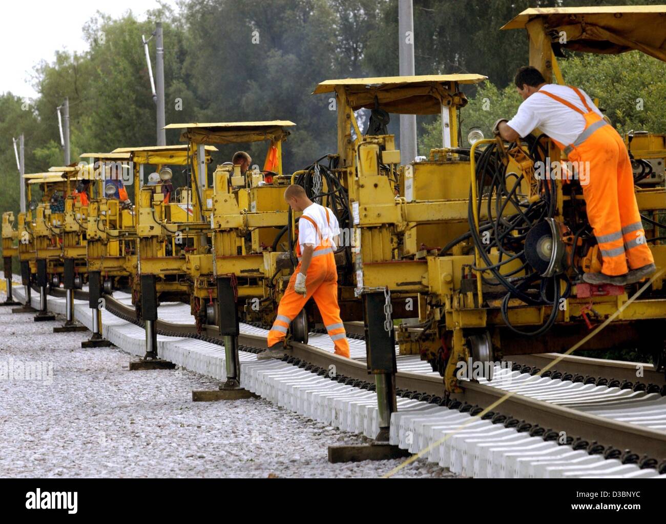 (Dpa) - eine spezielle Maschine hilft Arbeitnehmern eine 110 m lange Strecke auf dem Eisenbahn-Bett in der Nähe von Friesack, Deutschland, 28. August 2003 zu legen. Die Eisenbahnstrecke zwischen Berlin und Hamburg ist mit neuen Tracks für eine Geschwindigkeit von 230 km/h ausgestattet. Die Fahrt von Berlin nach Hamburg dauert dann nur 93 Minuten. Stockfoto