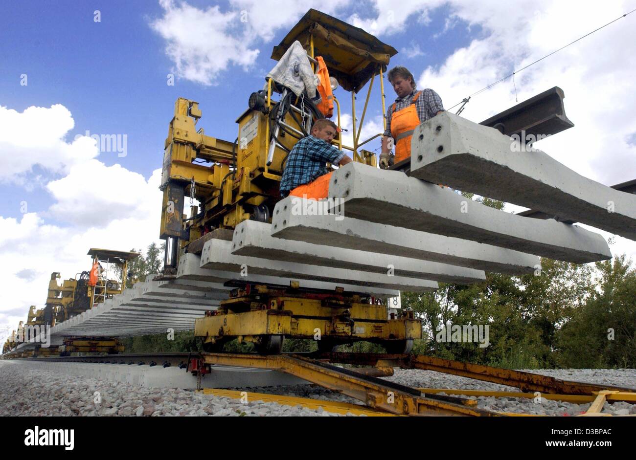 (Dpa) - eine spezielle Maschine hilft Arbeitnehmern eine 110 m lange Strecke auf dem Eisenbahn-Bett in der Nähe von Friesack, Deutschland, 28. August 2003 zu legen. Die Eisenbahnstrecke zwischen Berlin und Hamburg ist mit neuen Tracks für eine Geschwindigkeit von 230 km/h ausgestattet. Die Fahrt von Berlin nach Hamburg dauert dann nur 93 Minuten. Stockfoto
