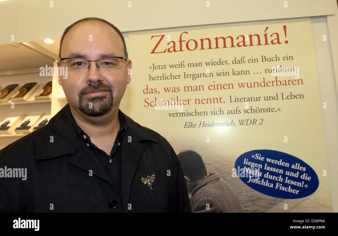 (Dpa) - der spanische Schriftsteller Carlos Ruiz Zafón präsentiert seinen Roman "Der Schatten des Windes" auf der Buchmesse in Frankfurt am Main, 9. Oktober 2003. Der Text auf der Wand liest "jetzt wieder, man weiß, dass ein Buch ein schönes Labyrinth sein kann... alles, was man nennt, ein wunderbares Buch. Literatur und live-Mix in Stockfoto