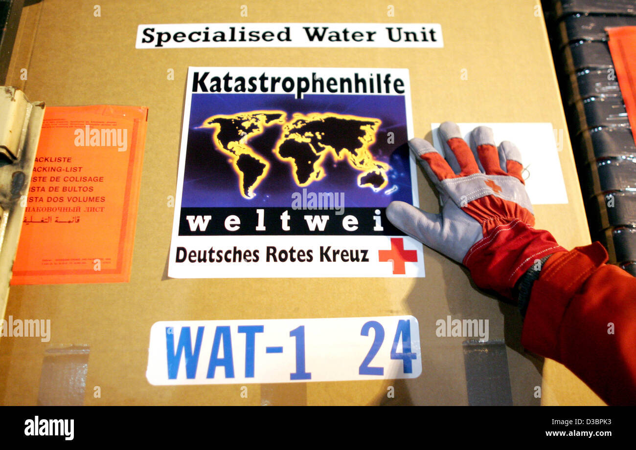 (Dpa) - ein Mitarbeiter des Deutschen Roten Kreuzes entlädt einen LKW, der mit zwei mobilen Süßwasser Einheiten geladen wird, die am Flughafen Köln/Bonn, Deutschland, 29. Dezember 2004 disjunkt sind. Das Deutsche Rote Kreuz schickt zwei mobile Süßwasser-Einheiten bis zu 120.000 Liter Uncontami produzieren können Stockfoto