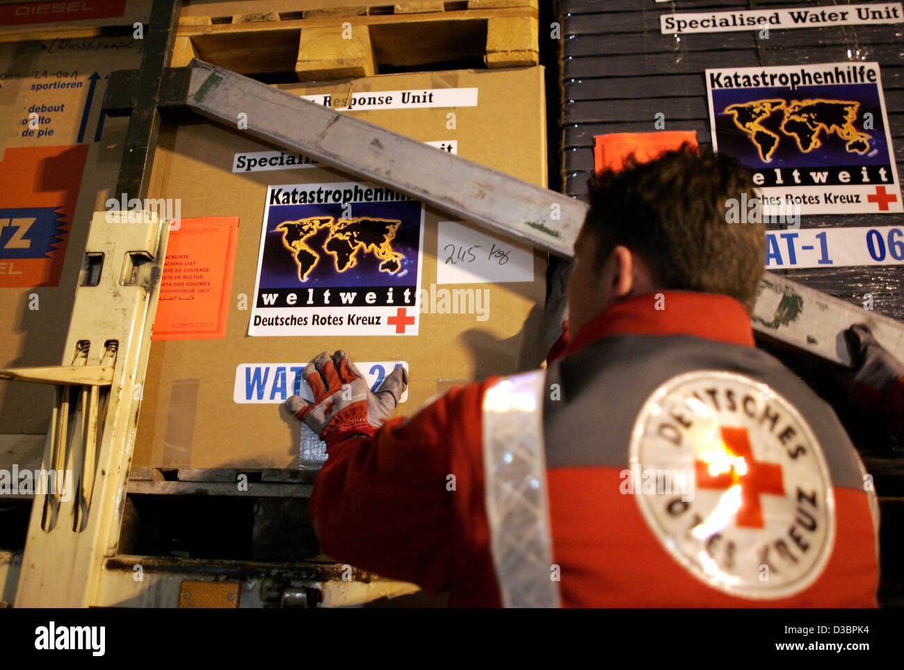 (Dpa) - ein Mitarbeiter des Deutschen Roten Kreuzes entlädt einen LKW, der mit zwei mobilen Süßwasser Einheiten geladen wird, die am Flughafen Köln/Bonn, Deutschland, 29. Dezember 2004 disjunkt sind. Das Deutsche Rote Kreuz schickt zwei mobile Süßwasser-Einheiten bis zu 120.000 Liter Uncontami produzieren können Stockfoto