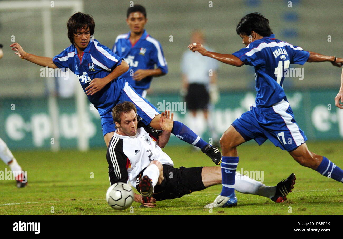 (Dpa) - fällt deutschen Verteidiger Andreas Hinkel (C) auf den Rasen in einem Duell mit Thailands Kittisak Siriwan (L) und Yuttajak Kongjan (R) im internationalen Testspiel zwischen Thailand und Deutschland im Rajamangala National Stadium in Bangkok, Thailand, Dienstag, 21. Dezember 2004. Stockfoto