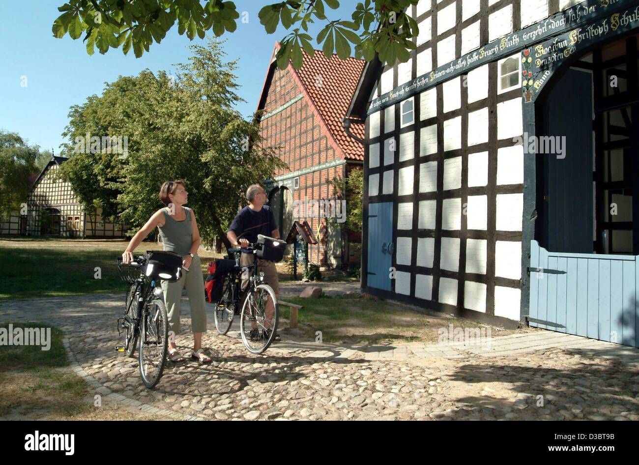 (Dpa) - Urlauber auf Fahrrädern Blick auf ein Fachwerkhaus in der kreisförmigen Dorf von Satemin, Norddeutschland, 18. August 2003. Die historischen Kreis-Dörfer sind typisch für die Region Wendland. Stockfoto