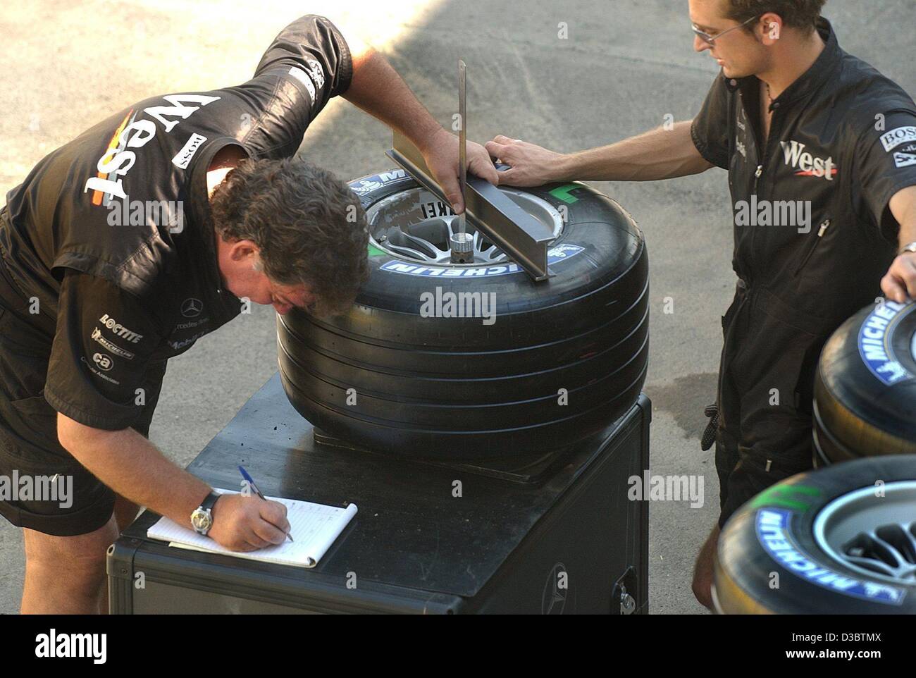 (Dpa) - Mechanik von McLaren-Mercedes Team akribisch nehme das Maß der Rennreifen, bei der Formel 1 Rennstrecke in Monza, Italien, 11. September 2003. Der neuen Michelin-Reifen scheinen mit den Motorsport-Regeln entsprechen. Die Formel eine Welt-Dachverband, FIA, erhielt McLaren und Williams die g Stockfoto