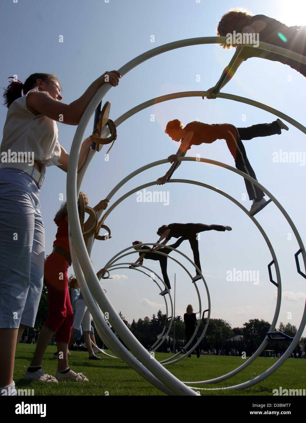 (Dpa) - eine Gruppe von Turnern wälzen einer Sportarena in einem Rhönrad während einer Werbeveranstaltung für Sport, in Nürnberg, 23. Juli 2003. Stockfoto