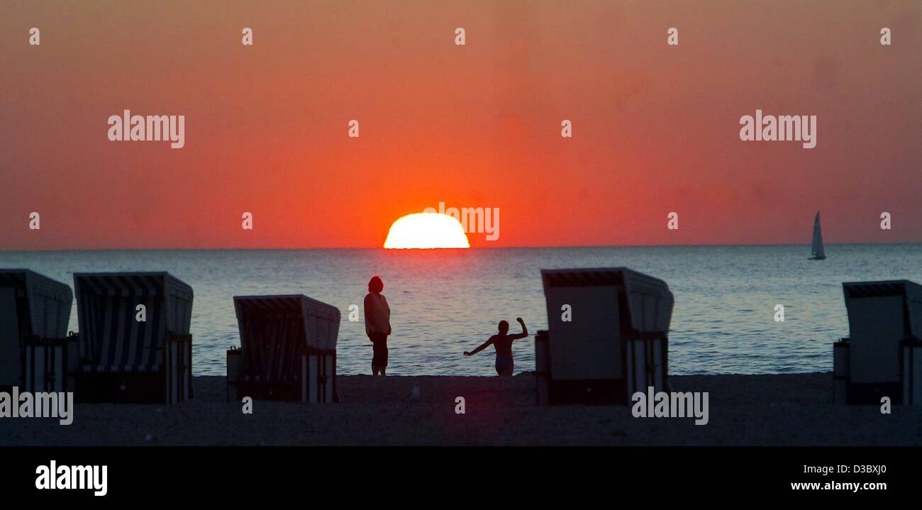 (Dpa) - die Sonne über den Horizont der Ostsee zwei Urlauber genießen die letzten Momente des Tageslichts am Strand in Warnemünde, Deutschland, 10. August 2003. Stockfoto