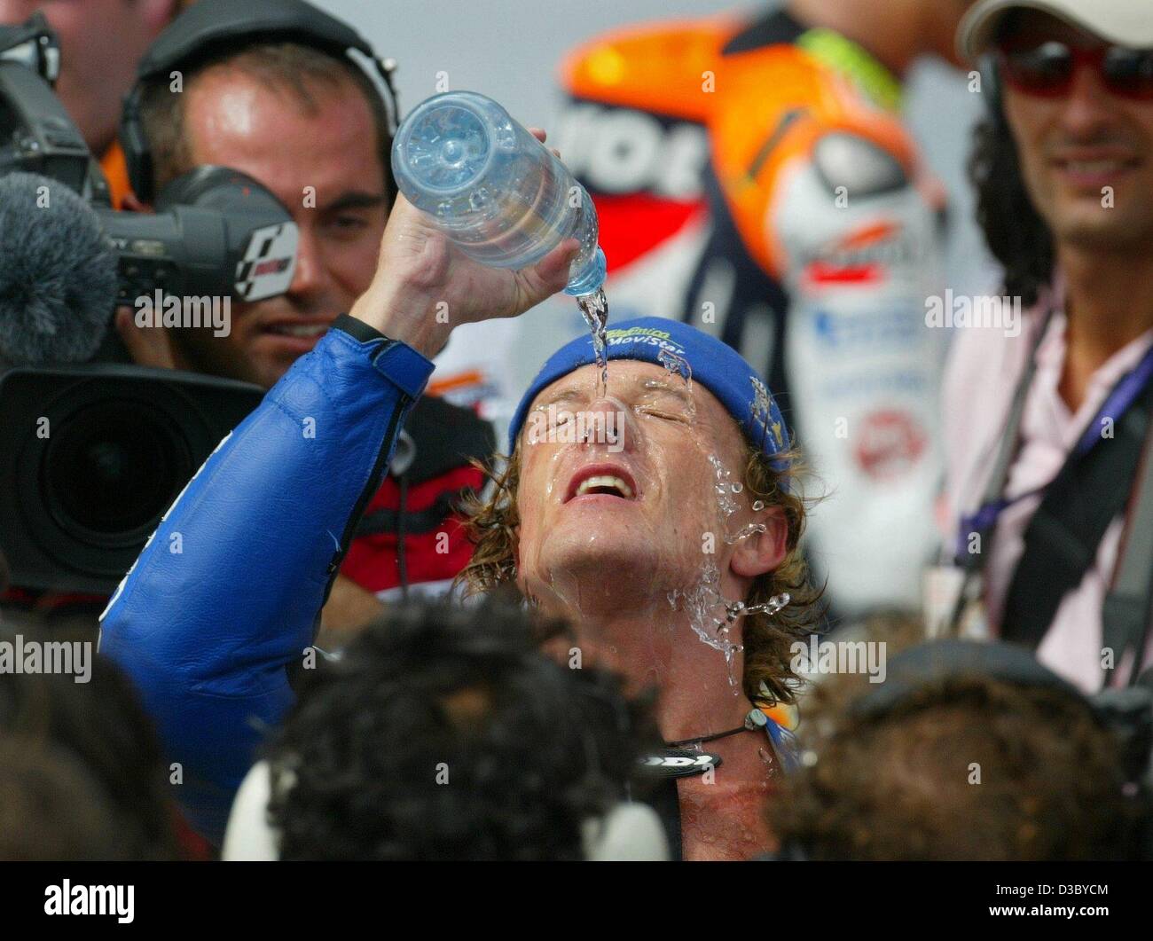 (Dpa) - spanische Motorrad-Pilot Sete Gibernau (Honda) gießt eine Flasche Wasser über den Kopf zur Erfrischung nach dem Gewinn der MotoGP-Rennen des Grand Prix von Deutschland auf dem Sachsenring bei Hohenstein-Ernstthal, Deutschland, 27. Juli 2003. Es ist seinen vierten Sieg in dieser Saison. Stockfoto