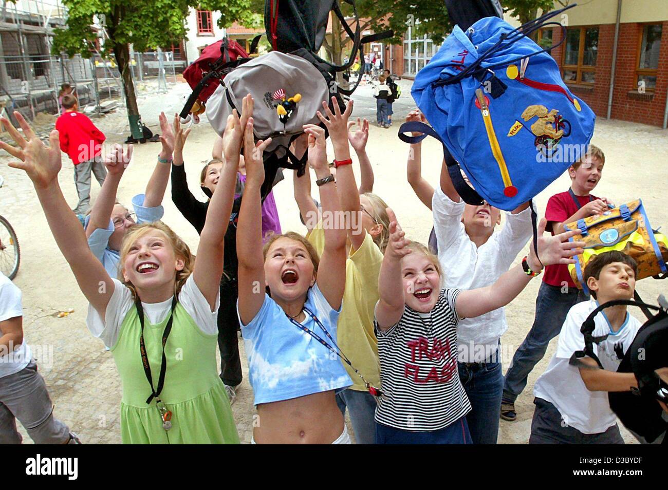 (Dpa) - die jungen und Mädchen einer Grundschule werfen ihre Schultaschen in die Luft wie es ihre letzten Schultag vor den Sommerferien in Schoeneiche bei Berlin, 2. Juli 2003. Stockfoto