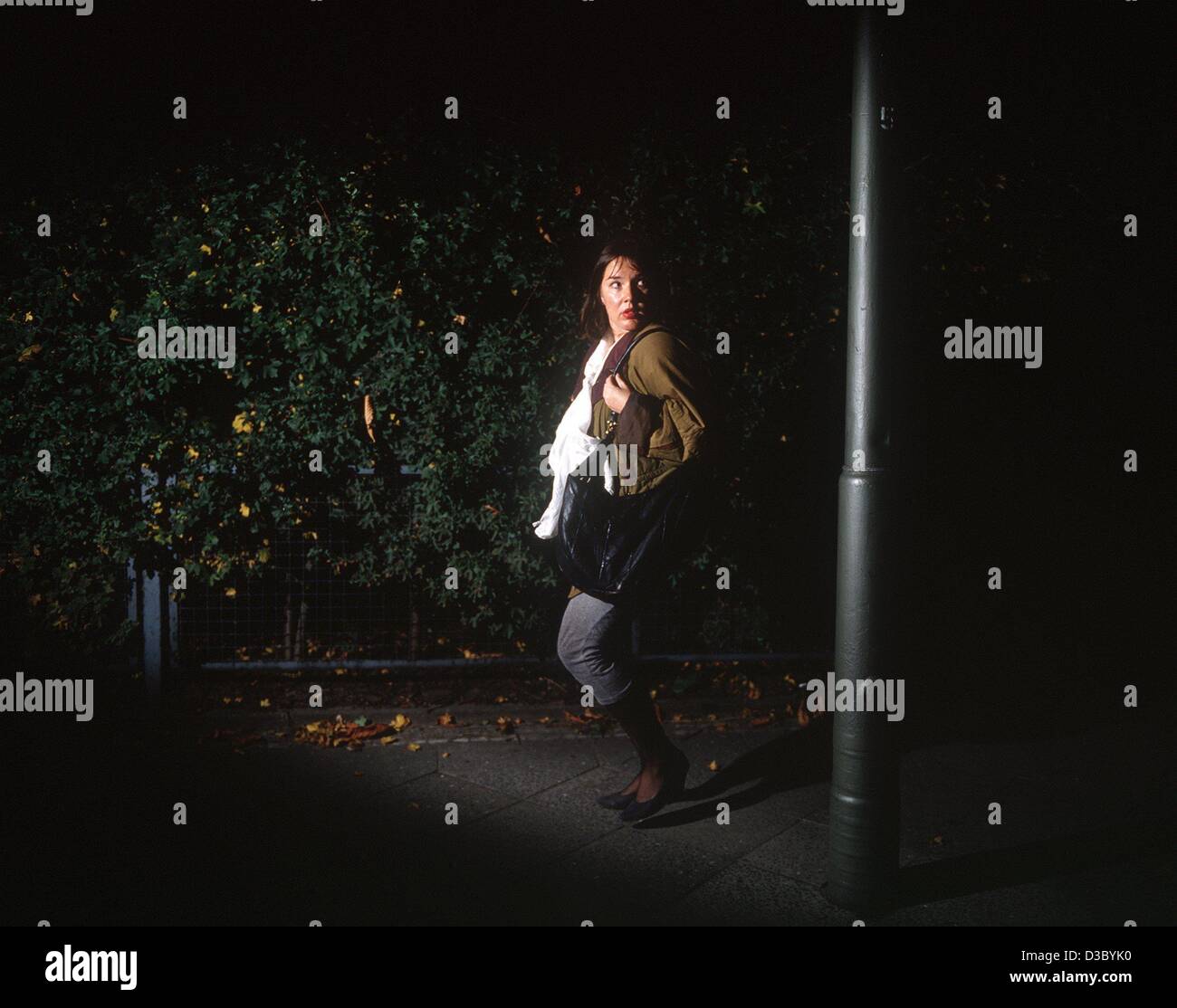 (Dpa-Dateien) - das symbolische Foto zeigt eine Frau allein zu Fuß auf einer Straße bei Nacht und Gefühl Angst durch einen großen Schatten (undatiert, den letzten Foto). Stockfoto