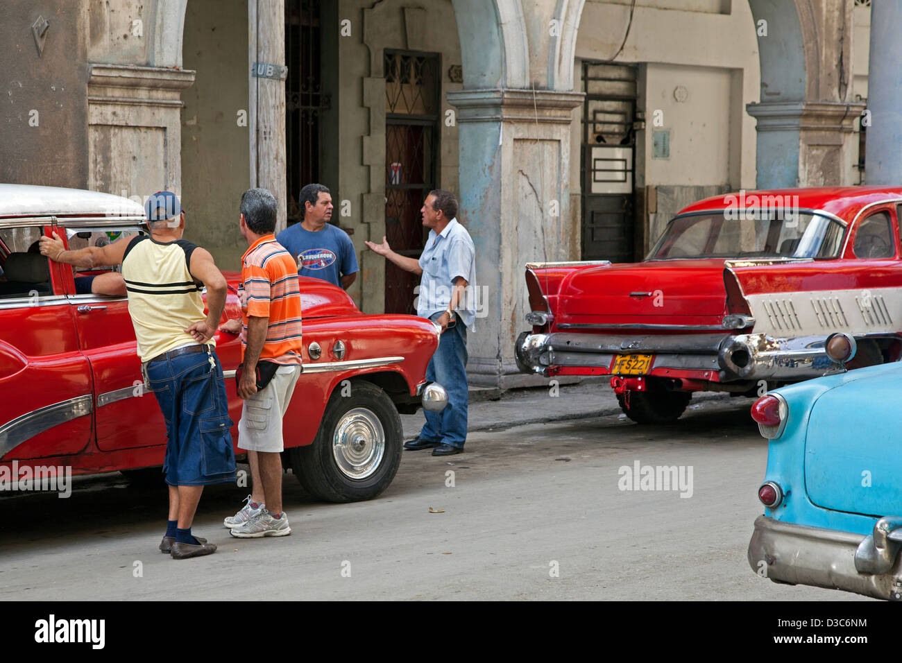 Kubanische Männer diskutieren über Straße und roten alten 1950er Jahre amerikanische Oldtimer / reißen Tank in Alt-Havanna / La Habana Vieja, Kuba Stockfoto