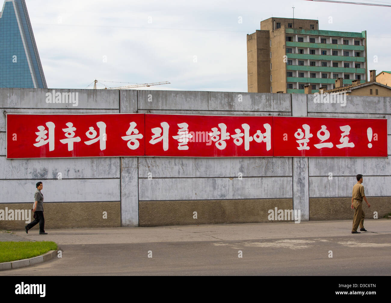 Nordkoreanische Passanten vor Propaganda-Plakat, Pyongyang, Nordkorea Stockfoto