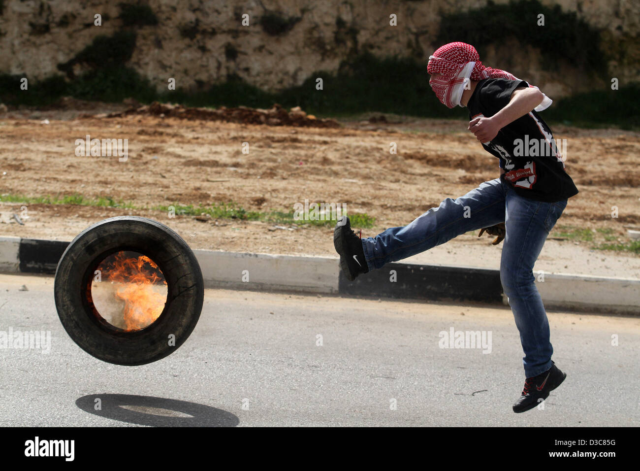 15. Februar 2013 - Ramallah, Westjordanland, Palästinensische Autonomiegebiete - A palästinensischen Demonstrant tritt einen verbrannten Reifen gegen israelische Soldaten bei Zusammenstößen vor Ofer Gefängnis, in der Nähe von der Westbank Ramallah, nach einer Demonstration zur Unterstützung der palästinensischen Gefangenen, Samer Issawi, für mehr als 200 Tage und andere Gefangene im Hungerstreik in israelischen Gefängnissen am 15. Februar in den Hungerstreik getreten gewesen , 2013. Einer der Vereinten Nationen offiziell am 13. Februar, besorgt um das wohl der palästinensischen Häftlinge in israelischen Gefängnissen und insbesondere über den Zustand der Issawi (Credit Imag Stockfoto