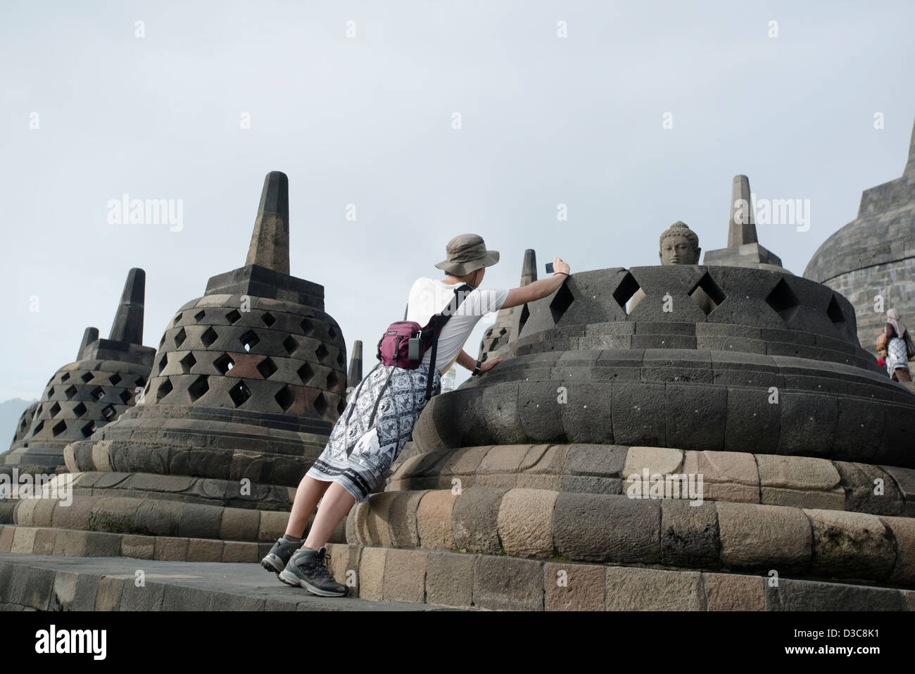 Ein Tourist nimmt ein Bild von einer Buddha-Statue im buddhistischen Tempel Borobudur auf Java, Indonesien Stockfoto