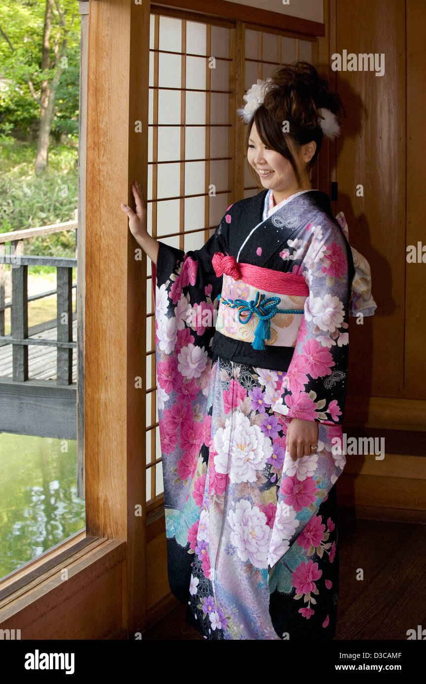Niedlich, lächelnden japanische Mädchen tragen traditionelle Furisode Langarm-Kimono mit Feder Blume Design in Fukui, Japan. Stockfoto