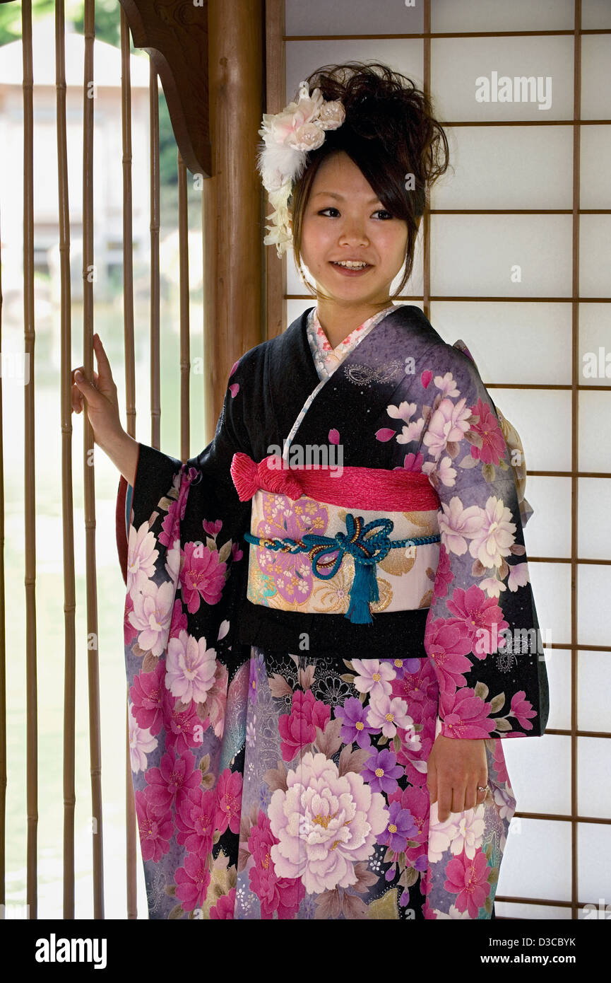 Niedlich, lächelnden japanische Mädchen tragen traditionelle Furisode Langarm-Kimono mit Feder Blume Design in Fukui, Japan. Stockfoto