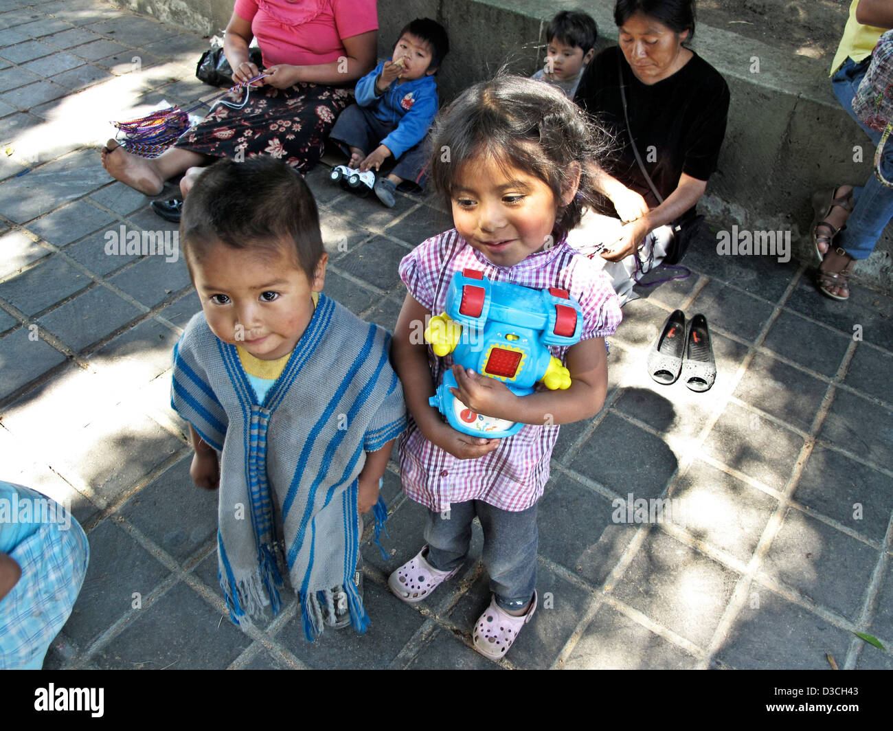 süße kleine mexikanischen indigenen Inderin umklammert Spielzeug mit kleinen hellen Augen Bruder in blau Sarape in Oaxaca Zocalo-Mexiko Stockfoto