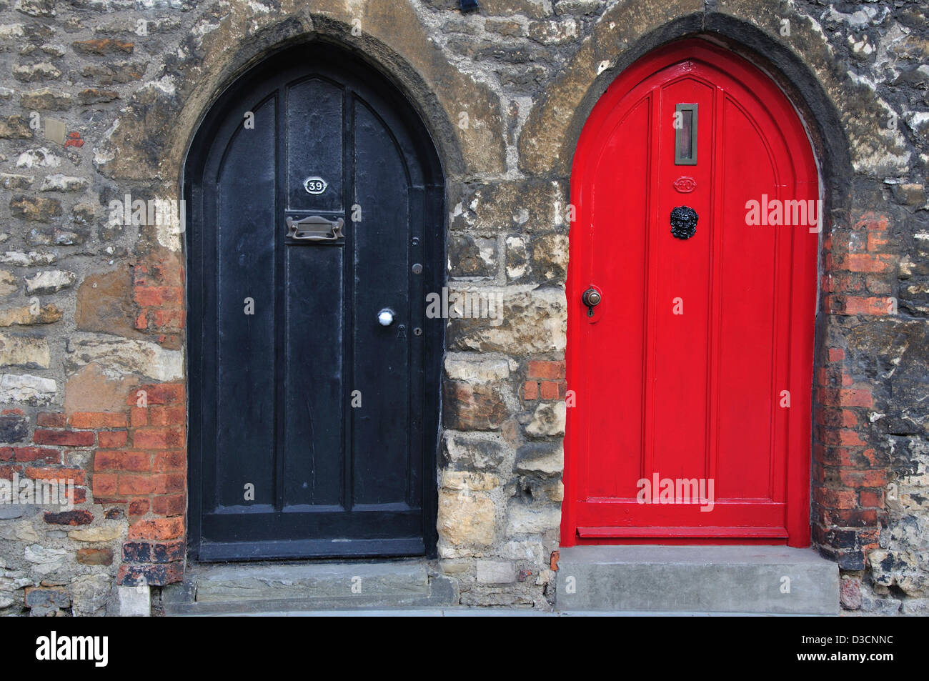 Zwei gewölbte Front Türen nebeneinander, eine rote, eine schwarze UK Stockfoto