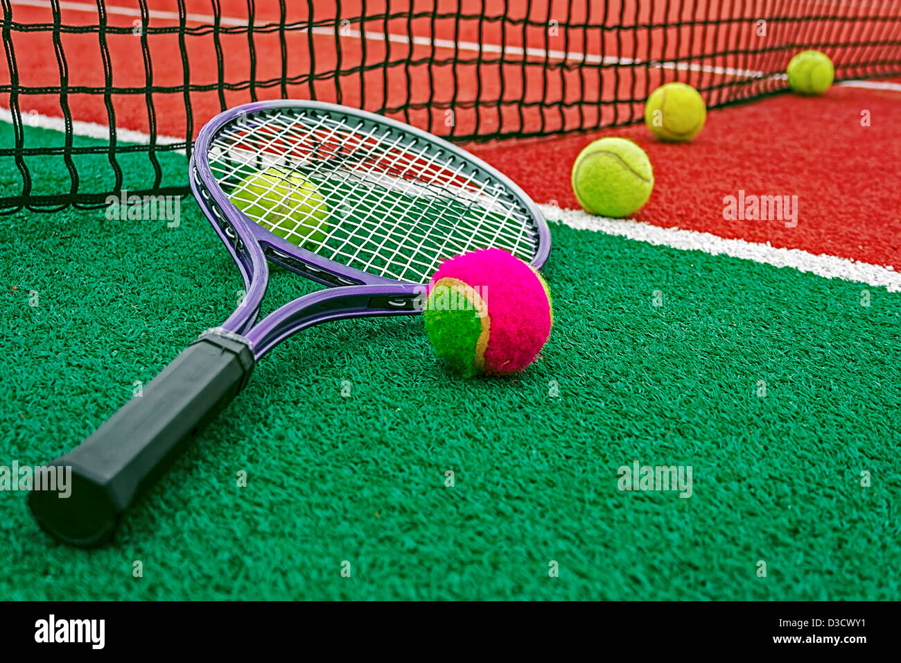 Ball und Tennis Schläger um das Netz auf einem synthetischen Feld angeordnet. Stockfoto