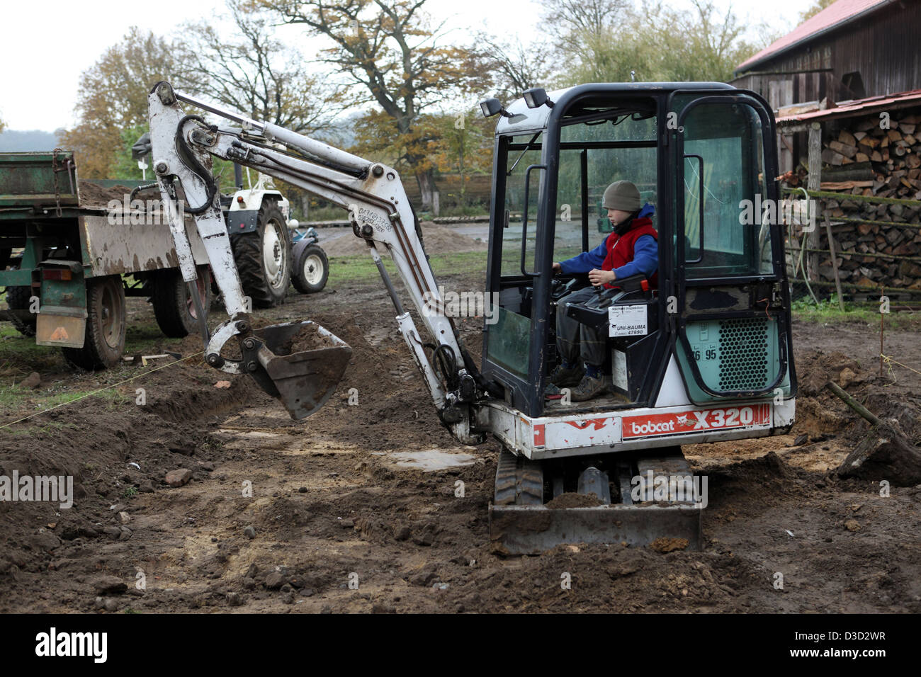 Strahlende Dorf, Deutschland, junge unbeaufsichtigt betrieben ein Minibagger Stockfoto