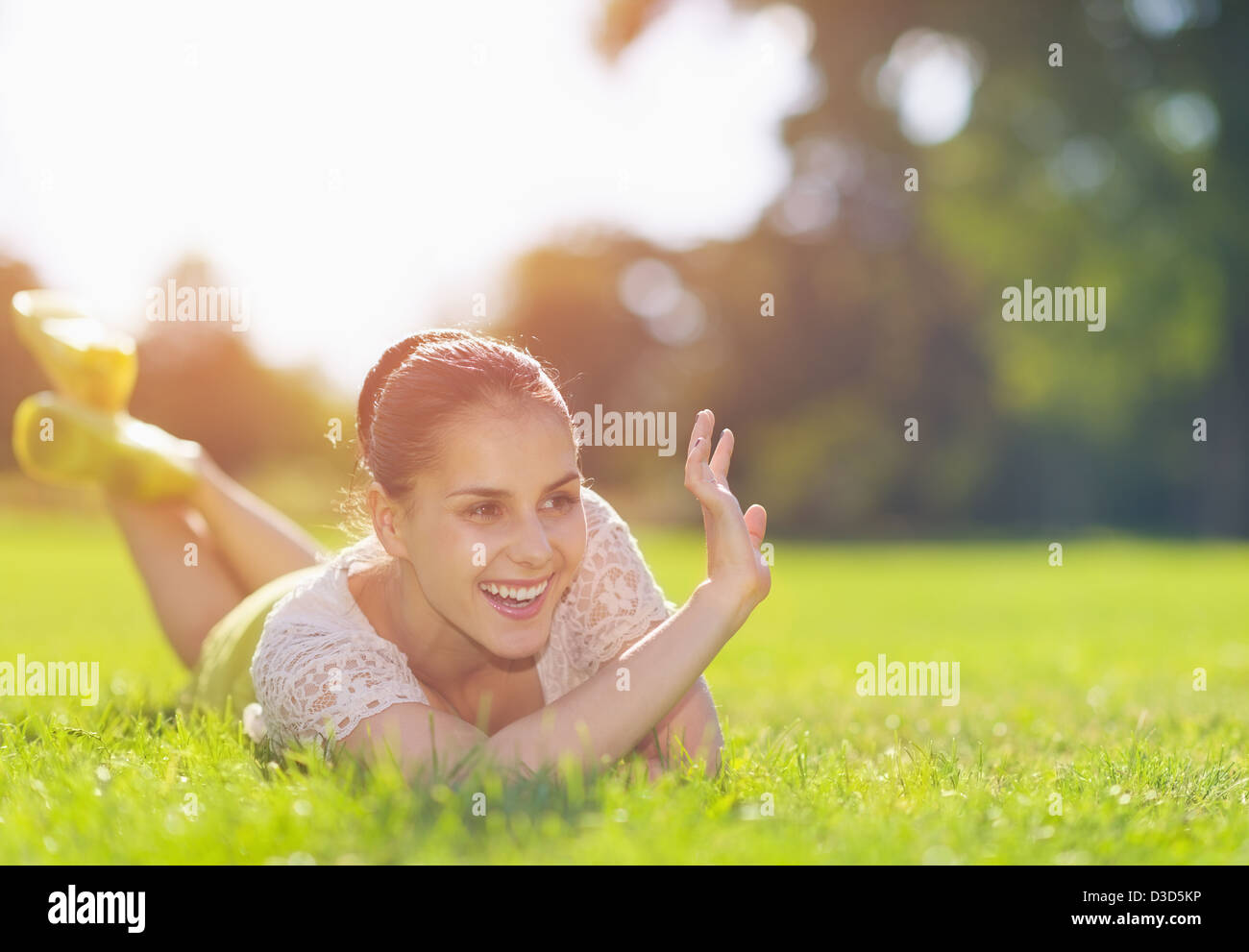 Glückliches Mädchen auf Wiese legen und grüßte Stockfoto